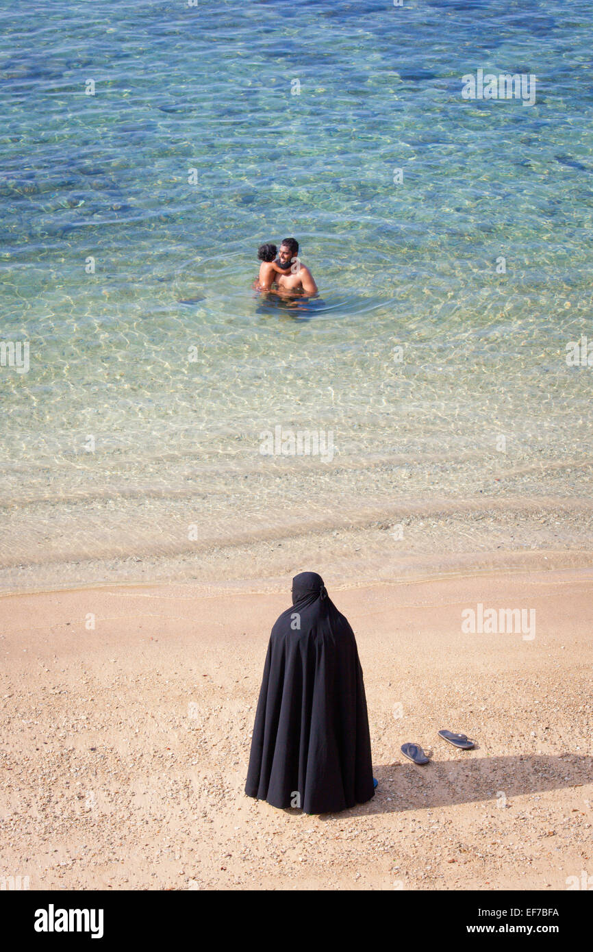 muslim-mother-in-burka-watching-husband-and-child-swim-EF7BFA.jpg